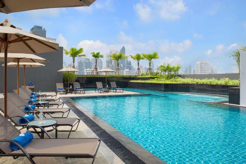 a swimming pool with chairs and umbrellas on a building at Hotel JAL City Bangkok in Bangkok