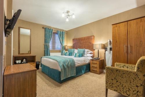 a hotel room with a bed and a chair at Hunday Manor Country House Hotel in Workington