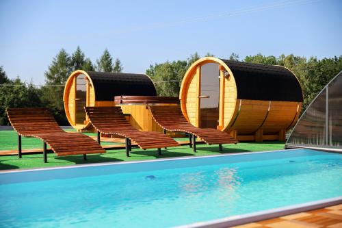 Ciężkowice的住宿－Zielona Osada，一组椅子和一个带圆形房子的游泳池