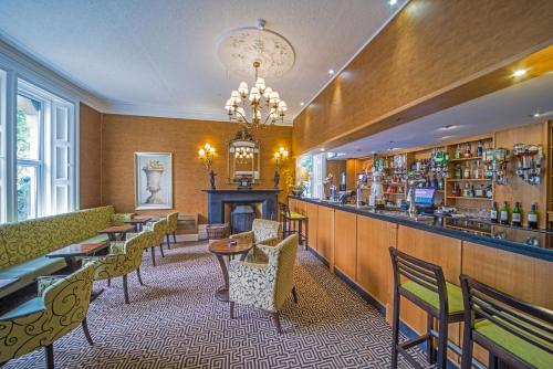 a restaurant with a bar and tables and chairs at Hunday Manor Country House Hotel in Workington