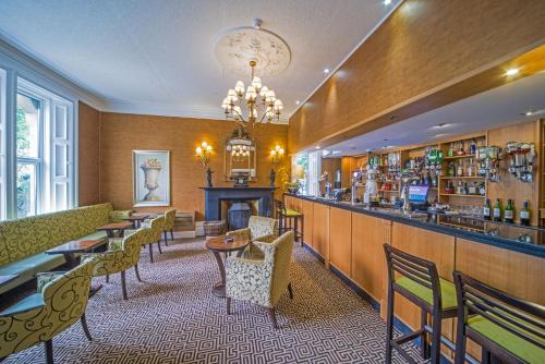 un restaurante con bar, mesas y sillas en Hunday Manor Country House Hotel, en Workington