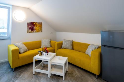 a living room with a yellow couch and a refrigerator at Aparthouse Jana Breg in Žirovnica
