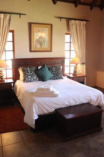 1 dormitorio con 1 cama grande con sábanas y almohadas blancas en Khaya Africa Guesthouse en Midrand