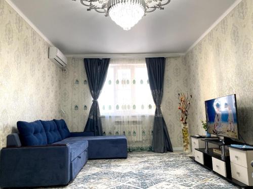 a living room with a blue couch in front of a window at Ясауи аппартамент in Türkistan
