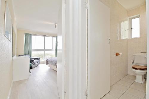a bathroom with a toilet and a bedroom with a bed at Blouberg heights in Cape Town