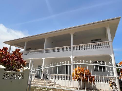 a white house with a white railing at Didi's Dream apartments in Anse Kerlan