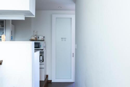 a kitchen with white cabinets and a white refrigerator at Cafe & Guest House Nagonoya in Nagoya