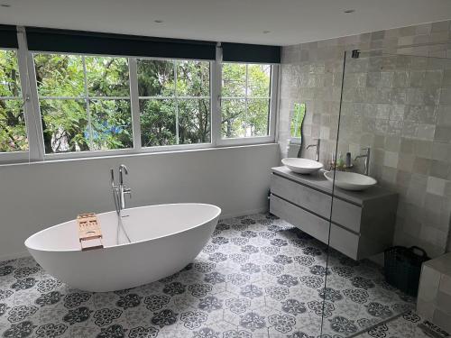 baño con bañera, 2 lavabos y ventana en Kess Maison, Gehele villa met dakterras Enschede en Enschede
