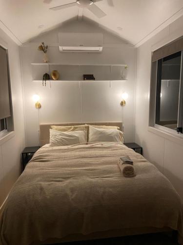 a bedroom with a large bed with a ceiling fan at Little Lodge - Luxury Tiny Home Stay in Alstonville
