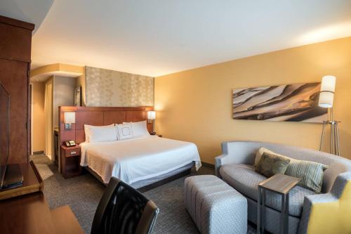a hotel room with a bed and a couch at Courtyard by Marriott Waldorf in Waldorf