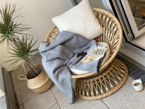 a wicker chair with a blanket and a pillow at Bremen Weser Best View Apartment in Bremen