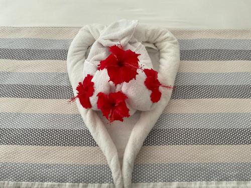 a white towel with red flowers on a bed at Didi's Dream apartments in Anse Kerlan