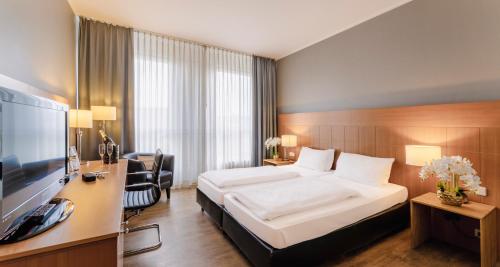 Habitación de hotel con cama, escritorio y TV. en PLAZA Premium Köln en Colonia
