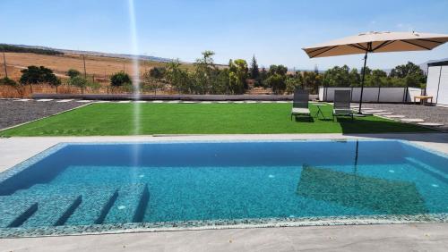 a swimming pool with an umbrella and a lawn at אריאה צימר בוטיק לזוגות Aria in HaZore‘im