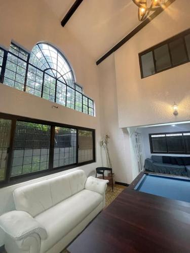 een woonkamer met een witte bank en een zwembad bij Spacious House in Tagaytay near Skyranch (6pax) in Tagaytay