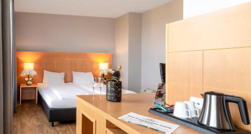 ケルンにあるPLAZA Premium Kölnのベッドとデスクが備わるホテルルームです。