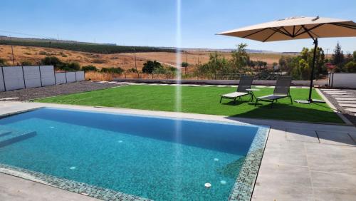 una piscina con sombrilla, mesa y sillas en אריאה צימר בוטיק לזוגות Aria, en HaZore‘im