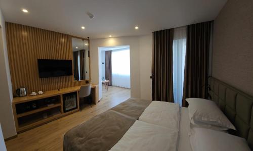 a hotel room with a bed and a flat screen tv at SIBB Hotel in Tirana