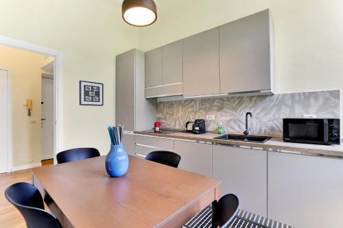 una cocina con una mesa de madera con sillas y un jarrón. en Appartamento Napoli 25 - Affitti Brevi Italia, en Milán