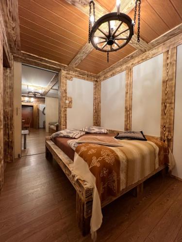 1 dormitorio con 1 cama grande y lámpara de araña en Apartamenty i Domki Taterka, en Kościelisko