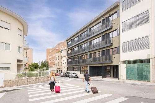 two people walking down a street with their luggage at Blissful Suites Porto by gaiarooms in Porto