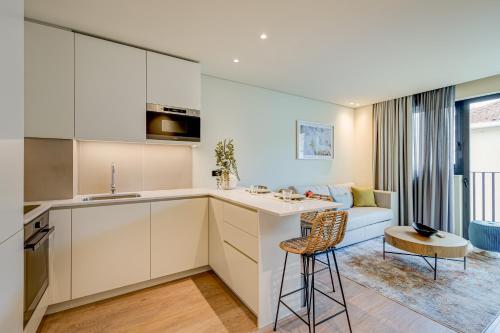 波尔图Blissful Suites Porto by gaiarooms的一间带白色橱柜的厨房和一间带沙发的客厅