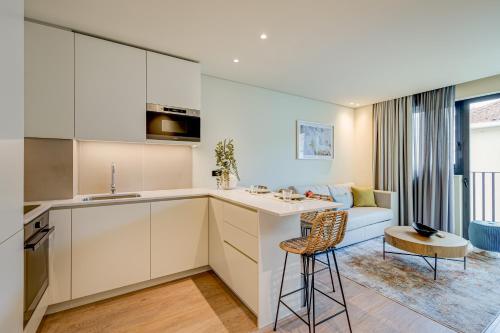 a kitchen with white cabinets and a living room with a couch at Blissful Suites Porto in Porto