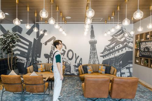 a man standing in a room with chairs and a wall at Travelodge Nagoya Sakae in Nagoya