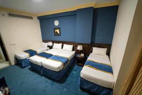 two beds in a room with blue walls at Al Barakah Mawaddah Hotel in Makkah