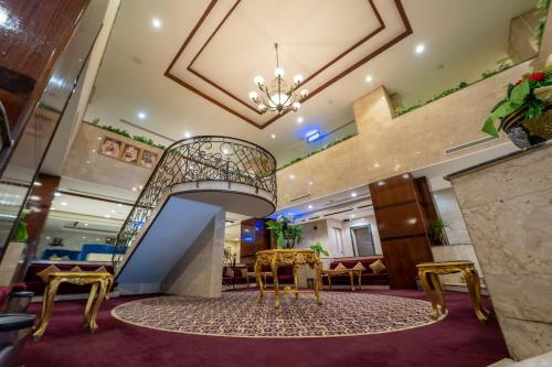a hotel lobby with a staircase and chairs at Al Barakah Mawaddah Hotel in Makkah