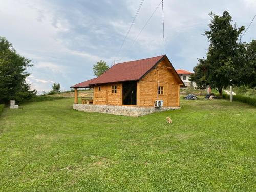 a small wooden house with a dog in a field at Vikendica Milošević in Arandelovac