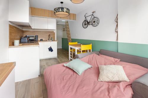 a bedroom with a pink bed and a kitchen at La Cabane des Bords de Loire in Saint-Sébastien-sur-Loire