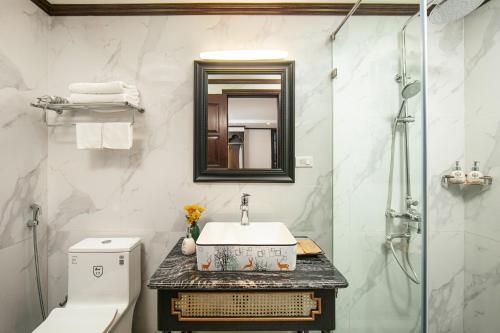 a bathroom with a sink and a toilet and a mirror at Media Central Hotel & Spa in Hanoi