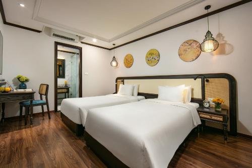 two beds in a hotel room with a desk and a room at Media Central Hotel & Spa in Hanoi