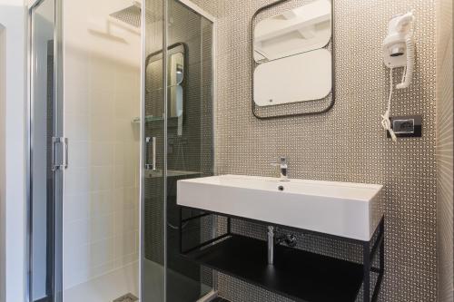 a bathroom with a white sink and a shower at La Maddalena Suite & Rooms in Bitonto