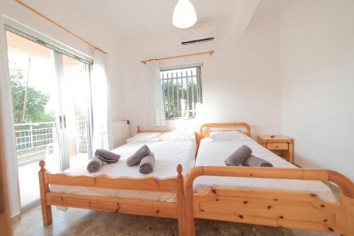 2 camas individuales en un dormitorio con ventana en Olive Apartments Elaionas, en Eleonas