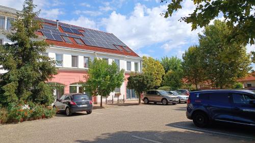 a parking lot with cars parked in front of a building with solar panels at Platan Hotel in Debrecen