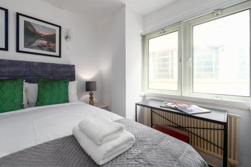 a bedroom with a bed with green pillows and a window at Piccadilly Circus by Capital in London