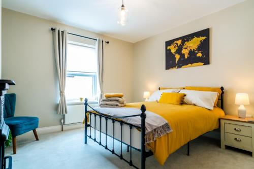 a bedroom with a yellow bed and a window at Steeple View House in Lincolnshire