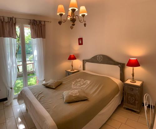 une chambre avec un lit avec deux lampes et une fenêtre dans l'établissement La maison au bord du lac, à Château-Guibert