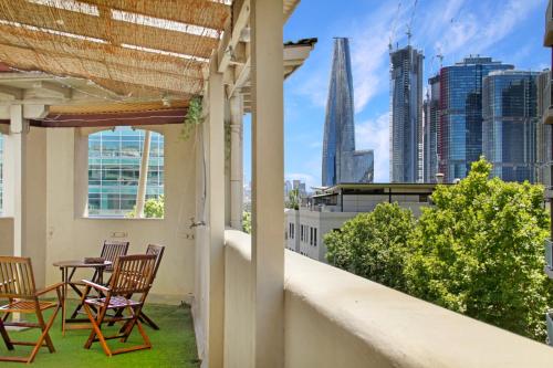 a balcony with chairs and tables and a view of the city at VENUS Harbourside - FEMALE ONLY HOSTEL in Sydney