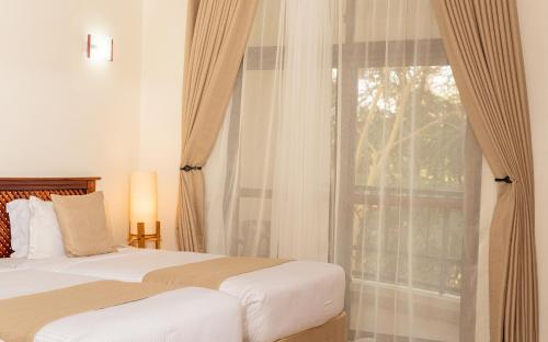 sypialnia z łóżkiem i dużym oknem w obiekcie Forest Hill Hotel w mieście Arusza