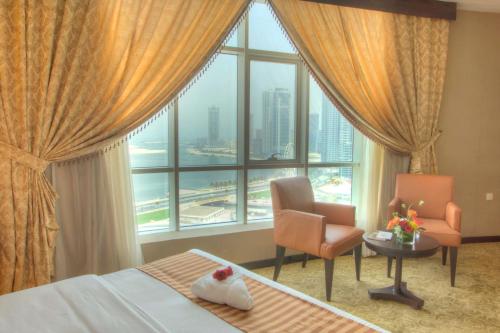 a hotel room with a bed and a chair and a window at Aryana Hotel in Sharjah