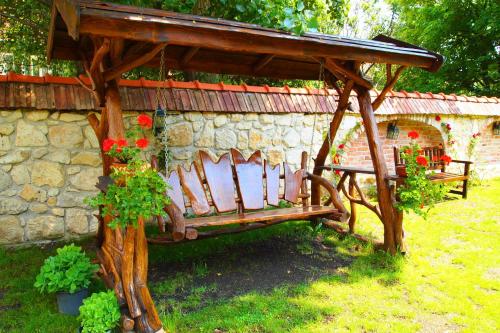 a wooden bench in front of a stone wall at Pensiunea Casa Dacilor in Podeni