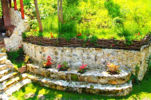 a garden with flowers in a stone wall at Pensiunea Casa Dacilor in Podeni