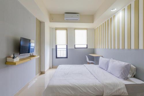 Schlafzimmer mit einem Bett, einem TV und Fenstern in der Unterkunft RedLiving Apartemen Evenciio - Arutala Living in Pondoktjina 1