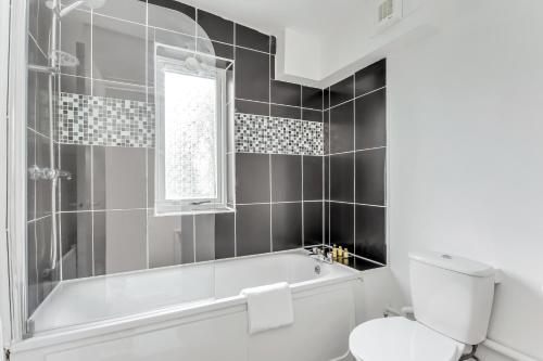 a bathroom with a tub and a toilet and a window at Aryas Apartments London in London