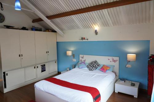 a bedroom with a large white bed with a blue wall at Church Hill Cottage in Ooty