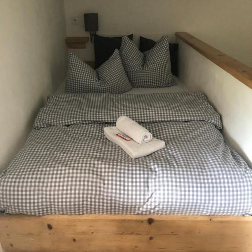 a bed with a wooden head board with a white towel on it at Haus Alpenglühen in Ehrwald