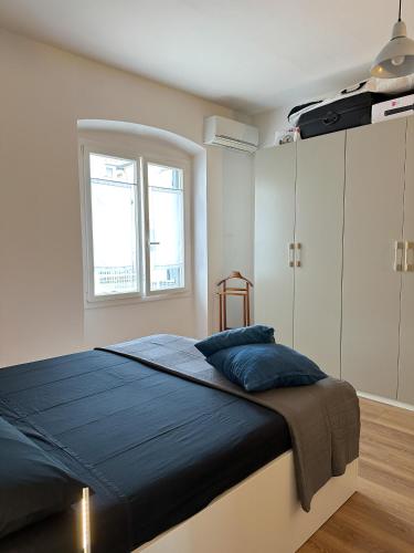 1 dormitorio con cama con sábanas azules y ventana en Urban Oasis Farini - Comodo Appartamento in Centro, en Milán